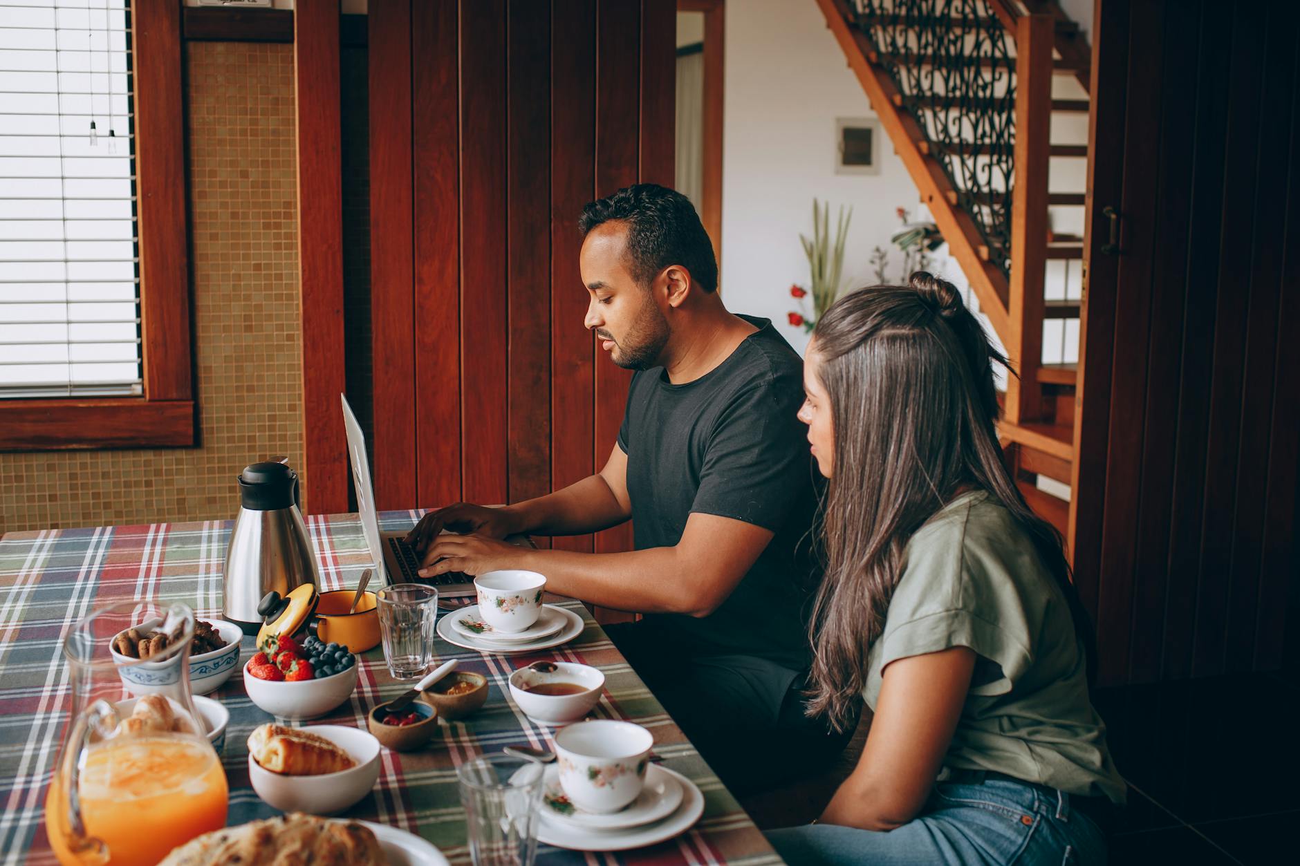 woman and man sitting at breakfast and working